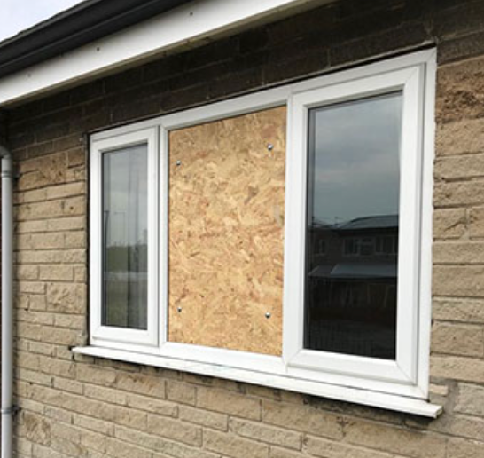 A brick building with a window that has been boarded up