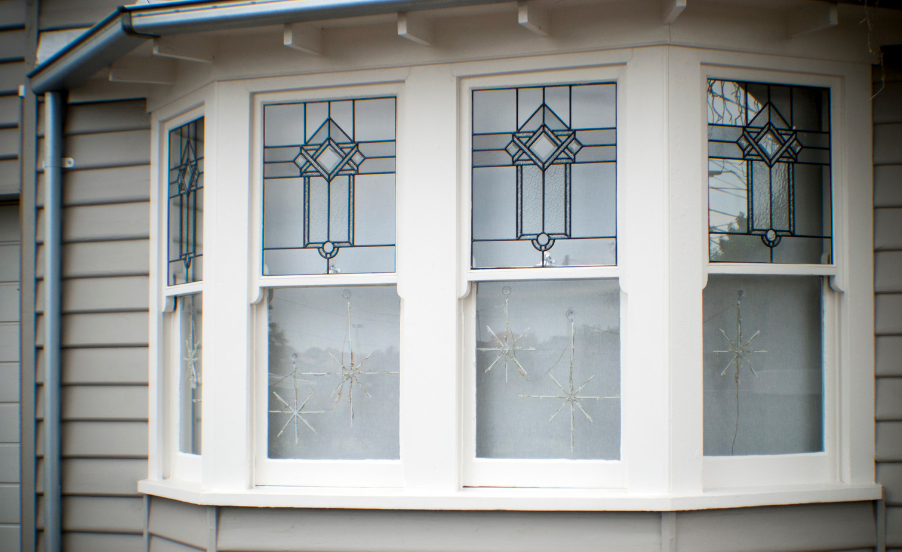 A white bay window with stained glass on a house