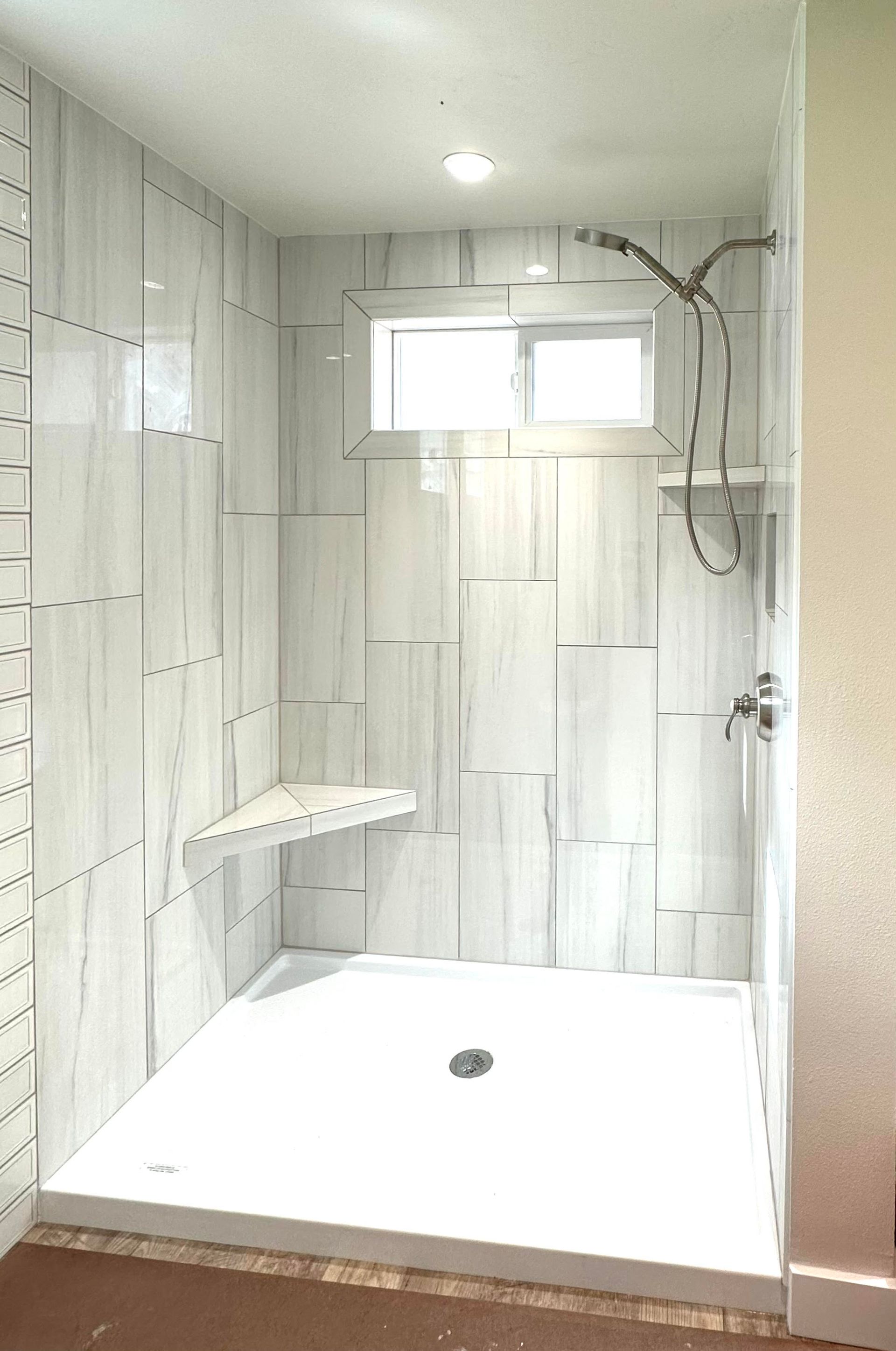 A bathroom with a walk in shower and a window.