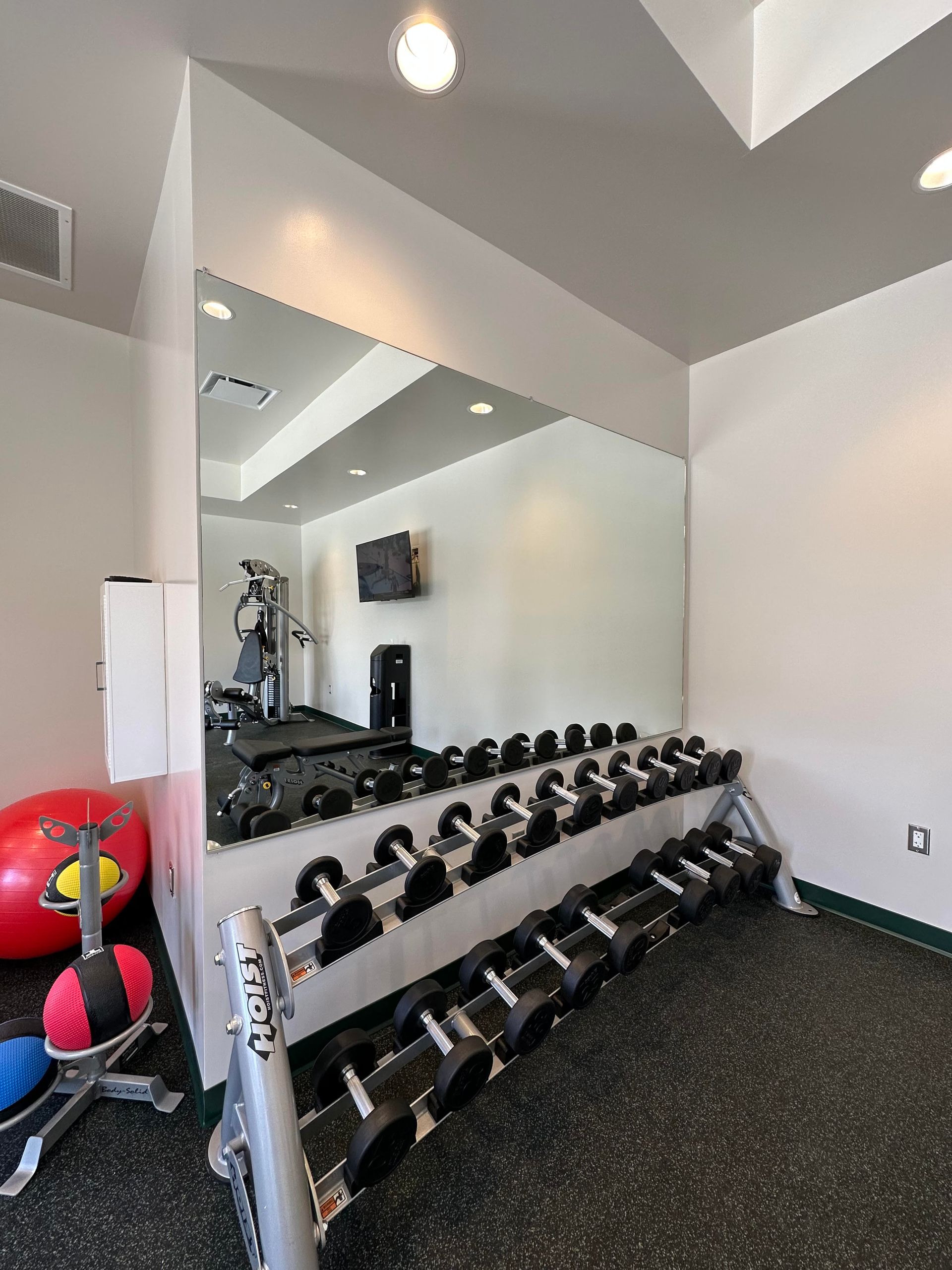 A gym with a lot of dumbbells and a large mirror