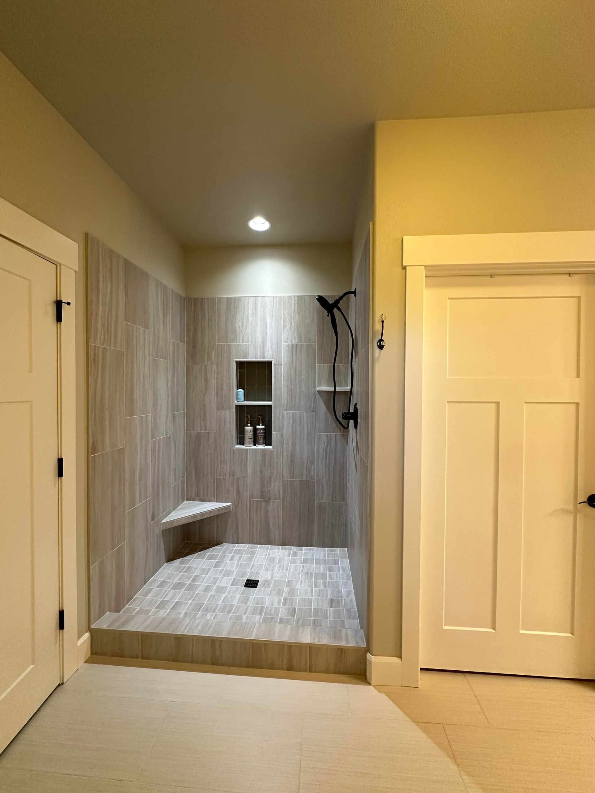 A bathroom with a walk in shower and a white door