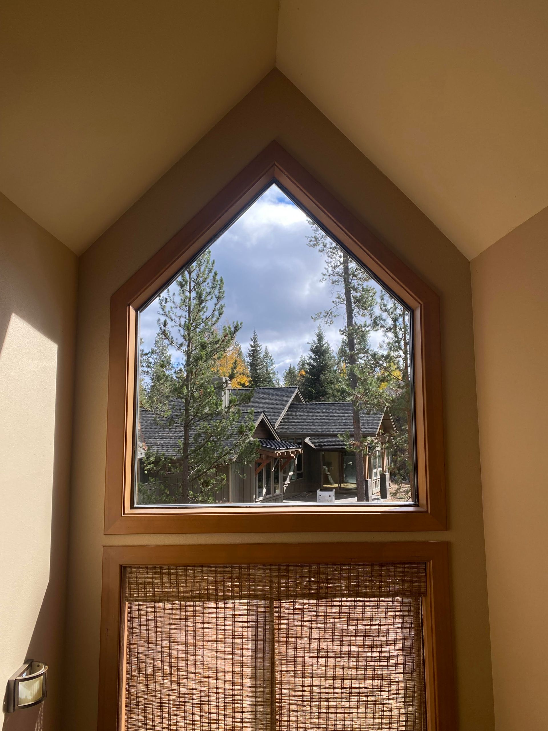 A large window in a room with a view of a house and trees.