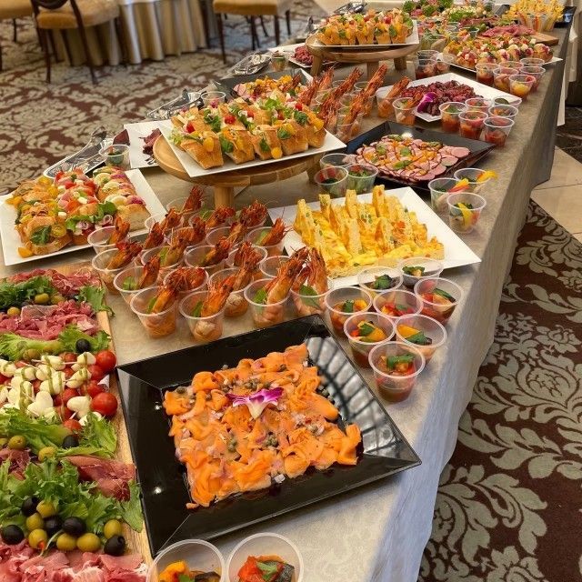 Buffet table with various appetizers: shrimp, smoked salmon, mini salads, and cheese.
