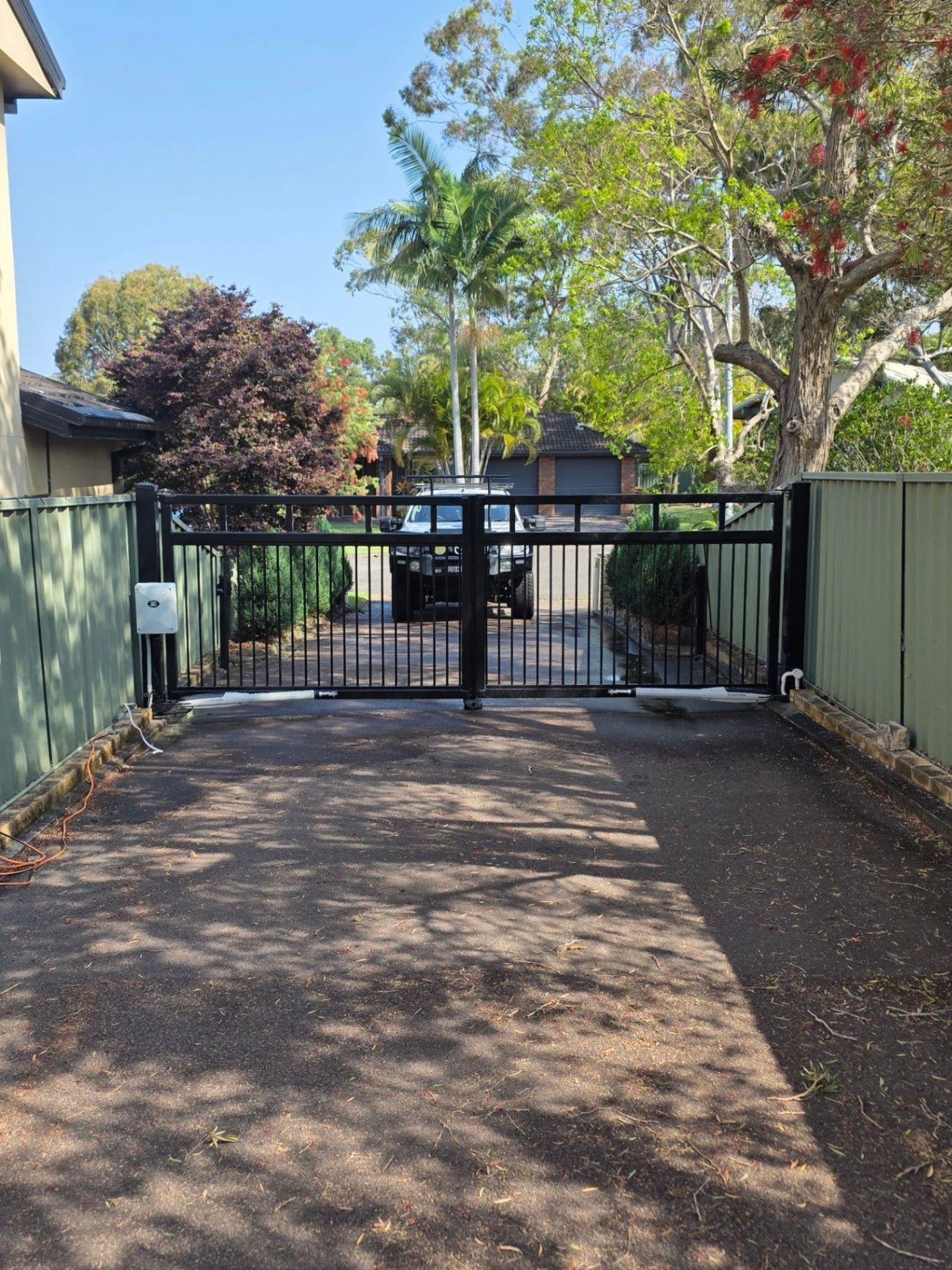 Driveway Leading to A Black Metal Gate, Flanked by Green Fences — Strike Fencing & Gates In Tuggerah, NSW