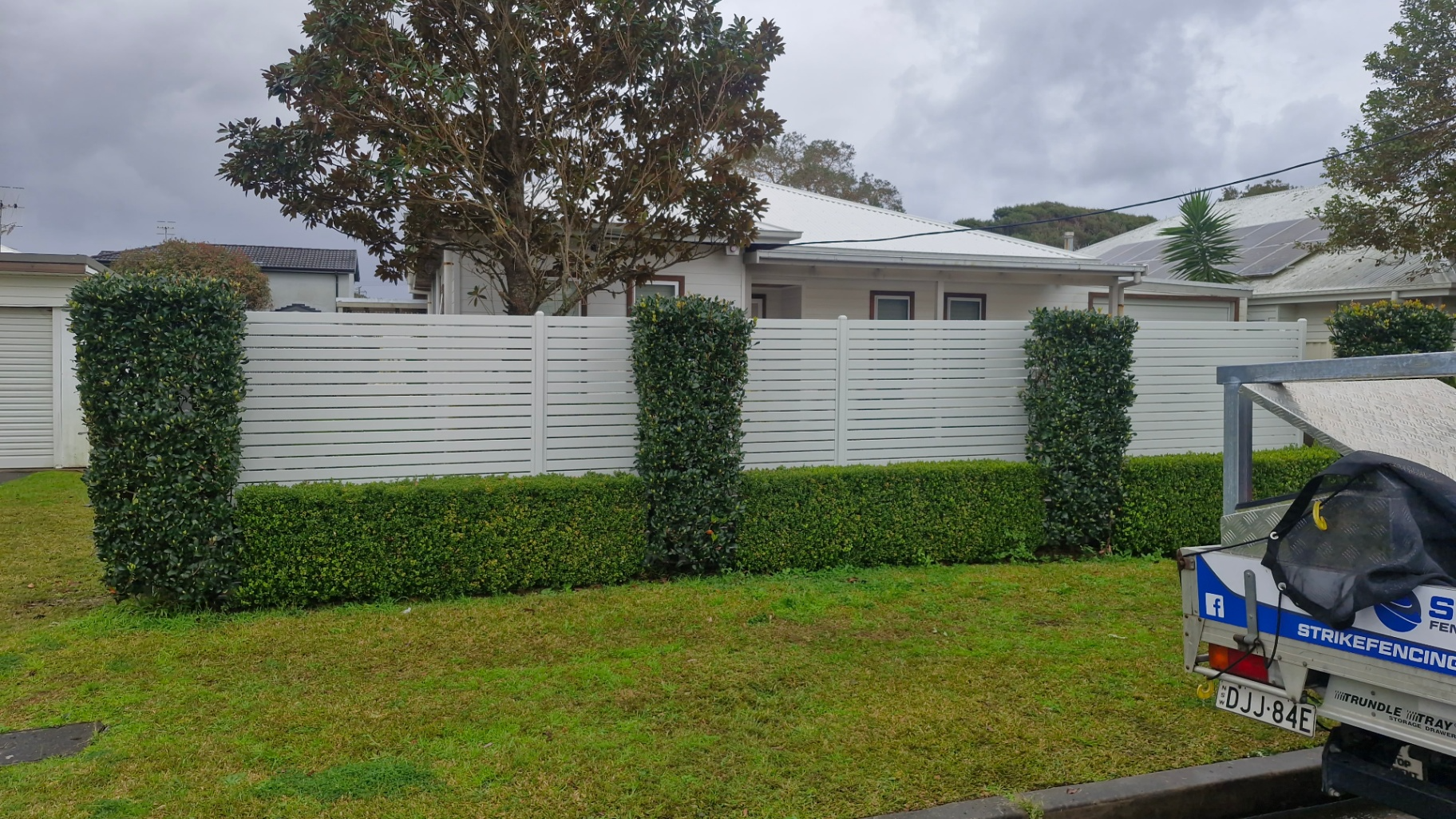White Slatted Fence With Green Hedges and Trimmed Columns — Strike Fencing & Gates In Tuggerah, NSW