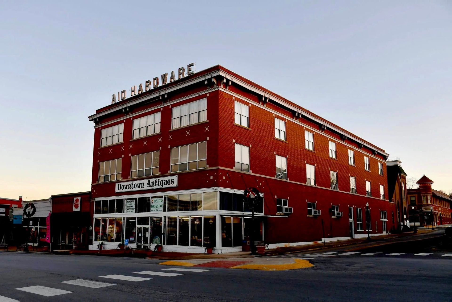 Red brick corner building with white trim at a street intersection at dusk