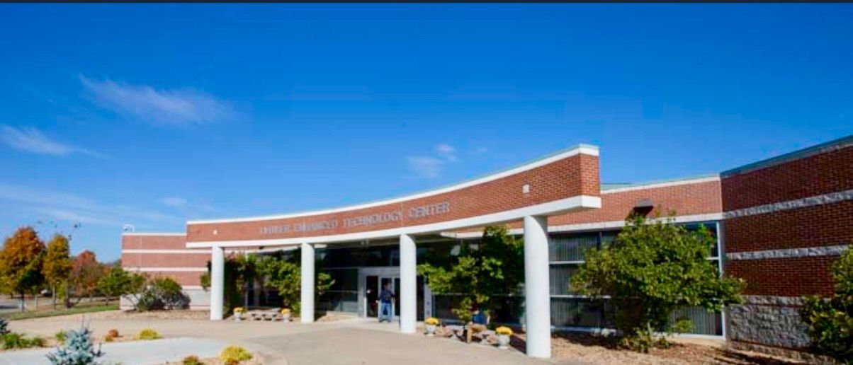 Modern brick building entrance with white columns and glass doors under a blue sky