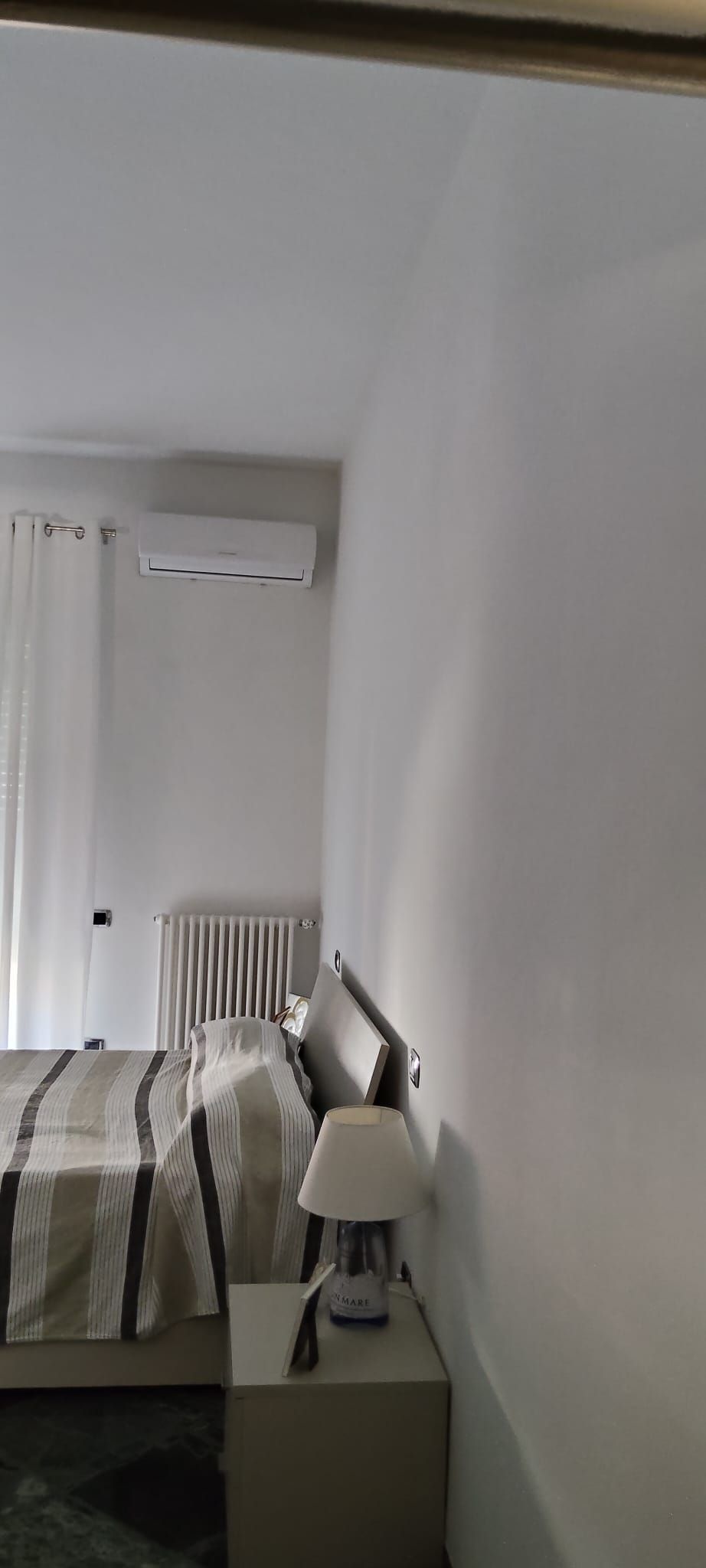 Una camera da letto con letto, comodino, lampada e aria condizionata.