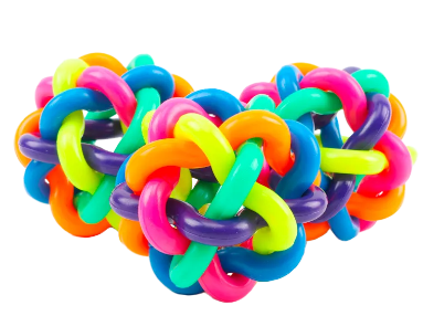 Un juguete para perros en forma de pelota anudada multicolor junto a un pequeño cachorro.