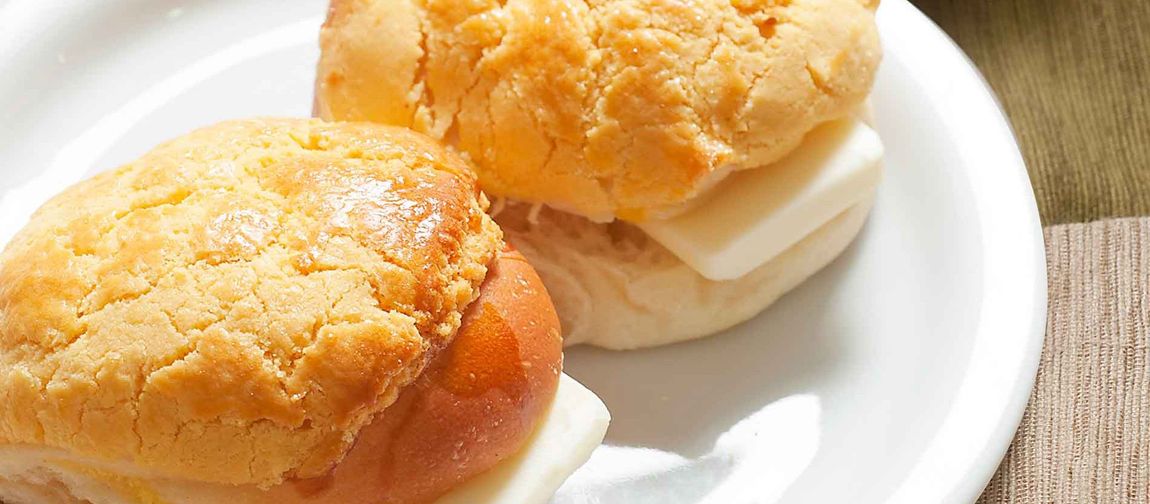 Two small biscuit sandwiches with white cream and peach filling on a white plate