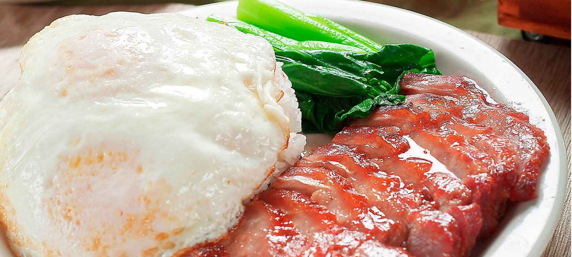 Plate of rice, grilled pork, and green vegetables on a white dish