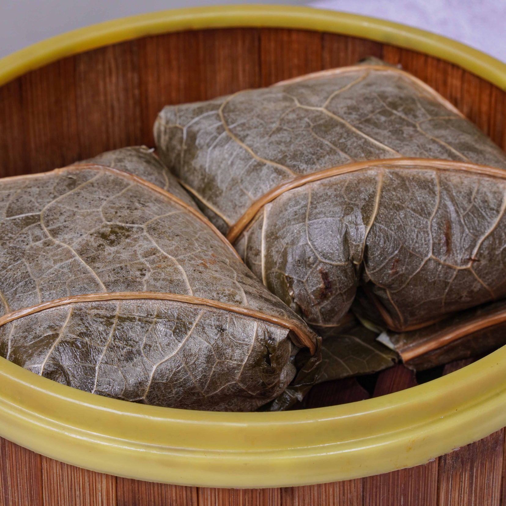 Two wrapped parcels in a yellow-rimmed bowl on a wooden table