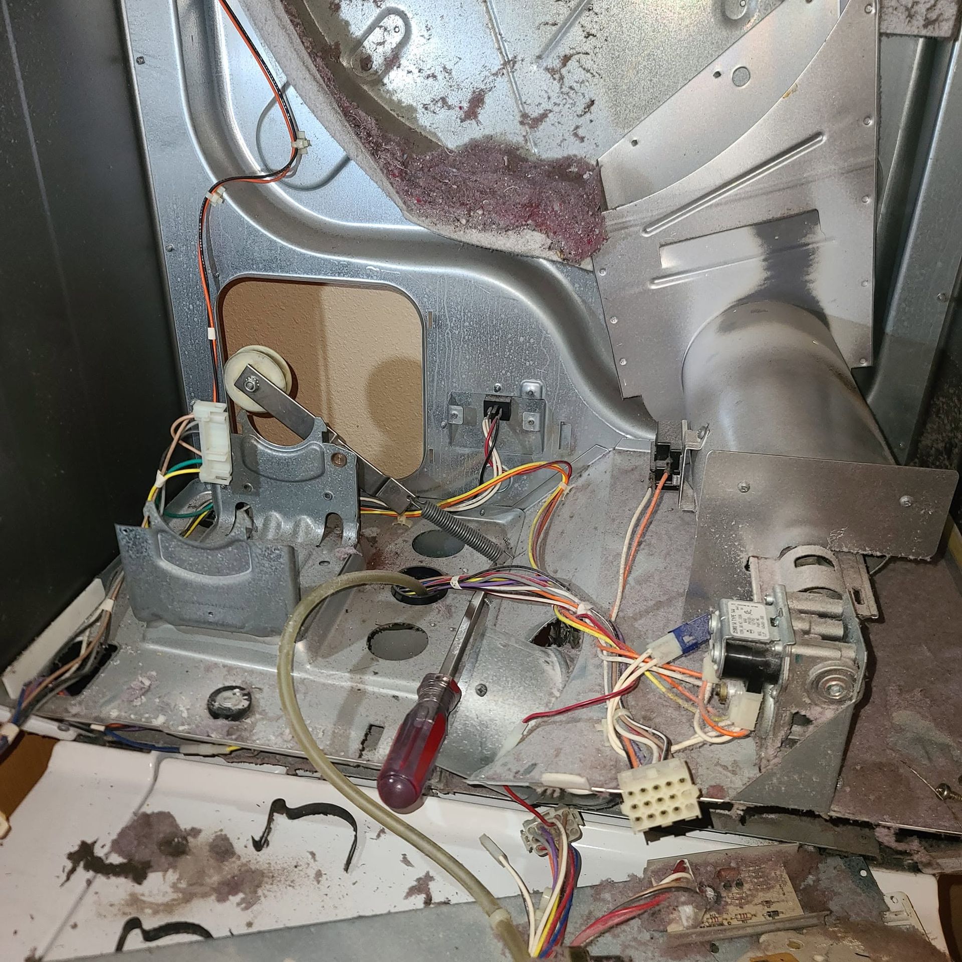 Open appliance interior with exposed wiring, metal housing, and a motor assembly on the floor.
