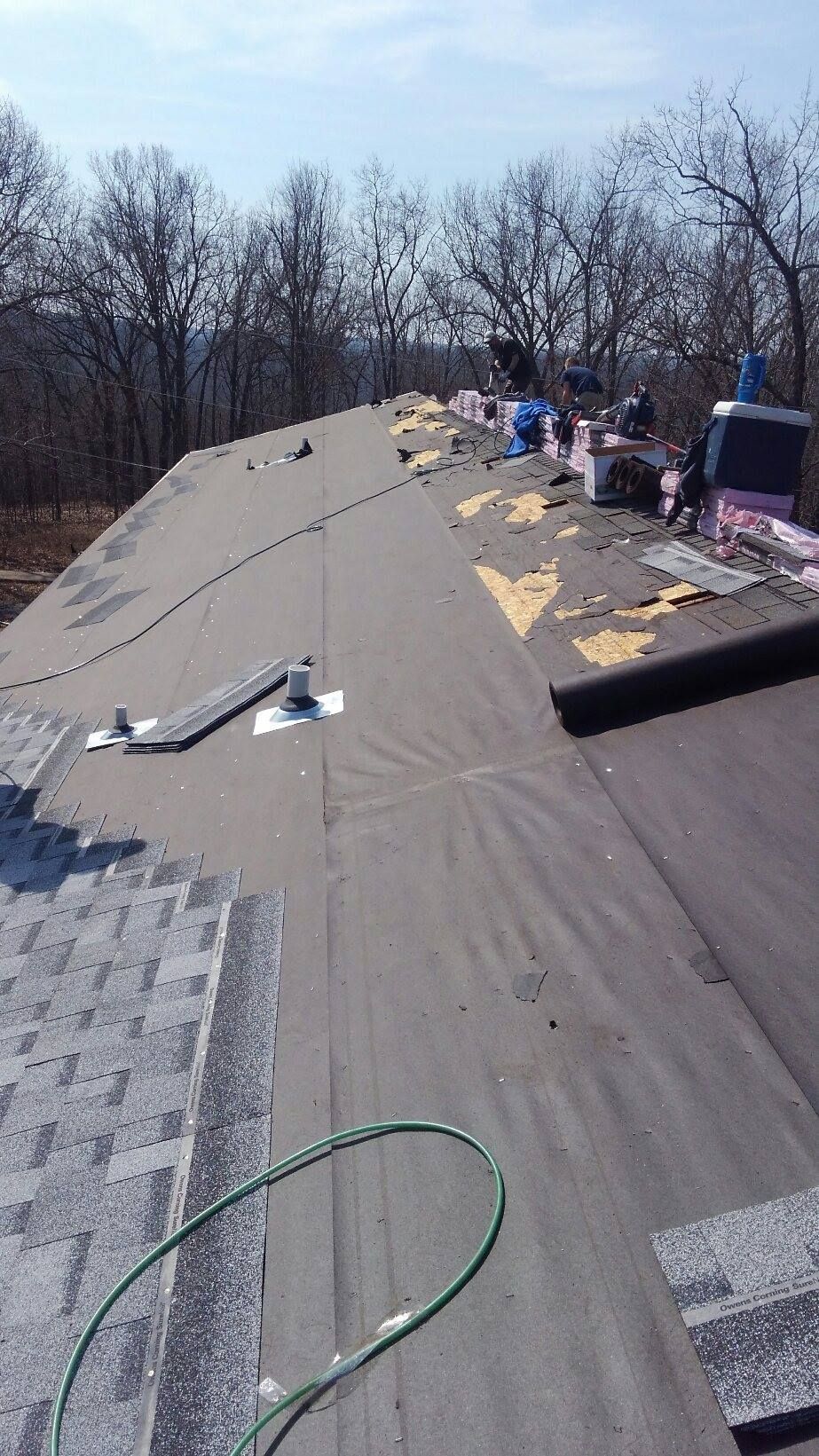 Roof under construction with shingles and materials on a sunny day.