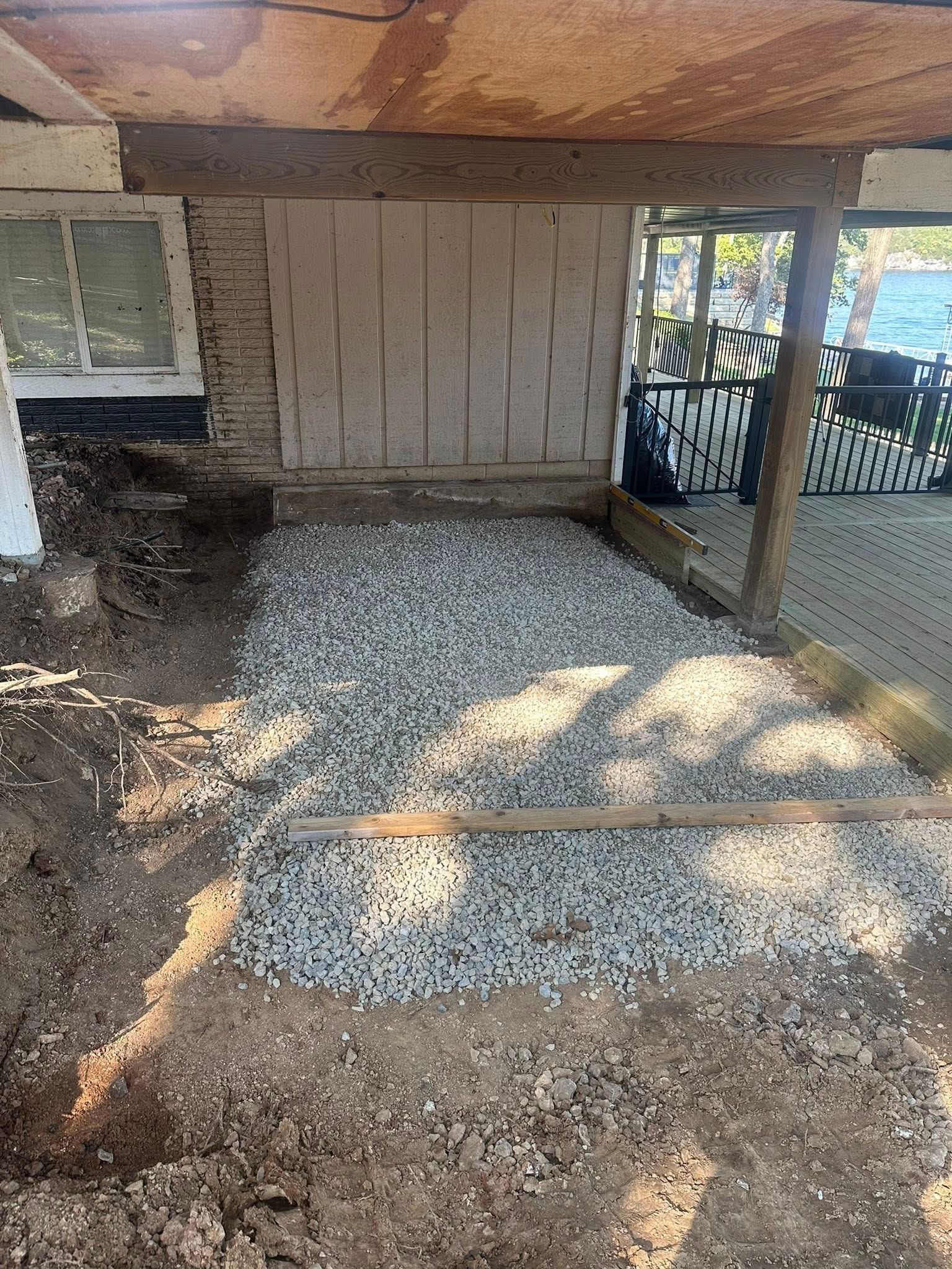 Gravel base laid under a porch. Dirt around the gravel, wooden beams support the porch ceiling.