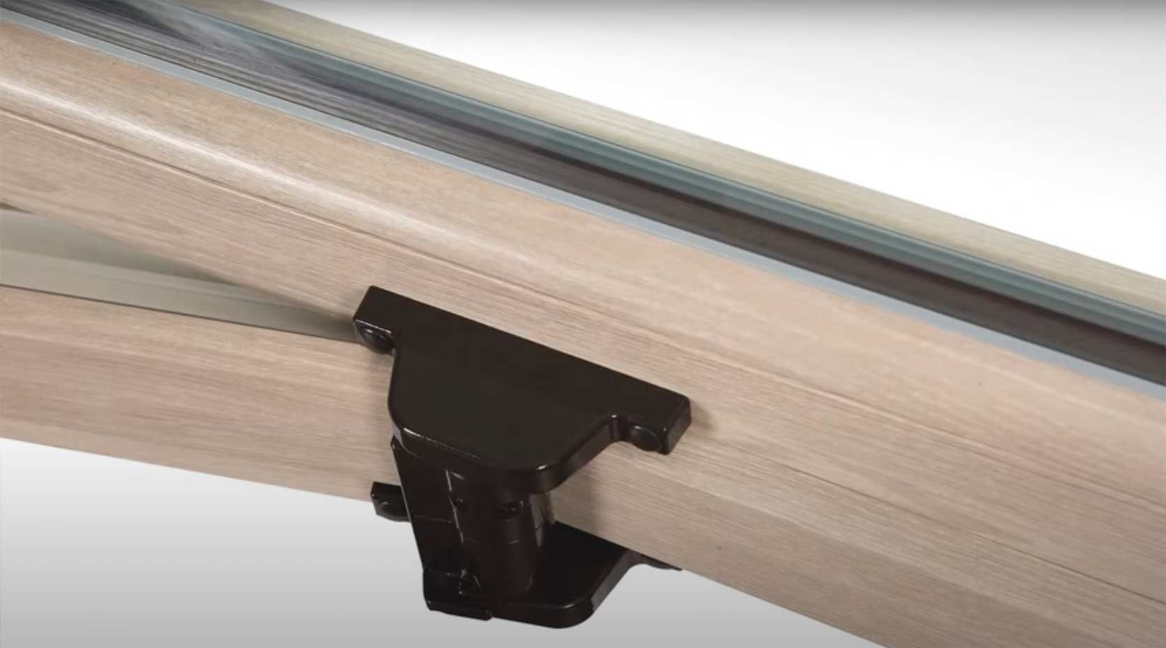 primo piano di una finestra in legno a cui è fissata una staffa metallica