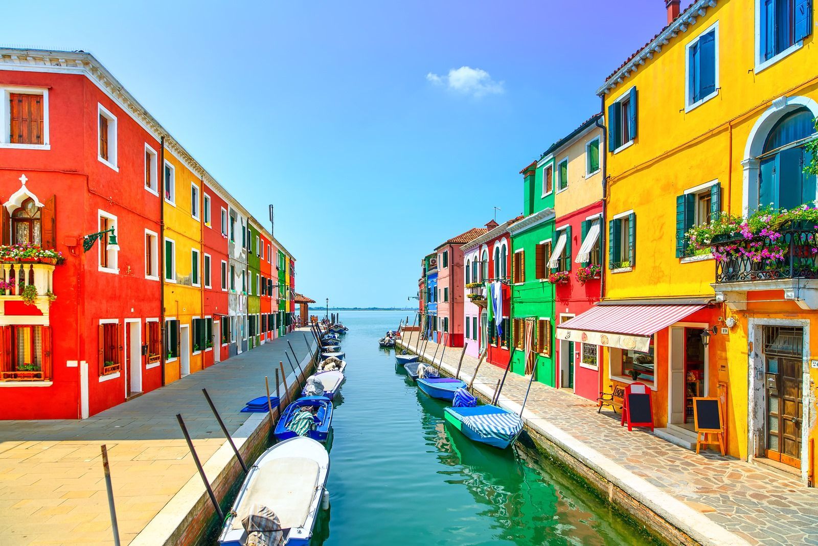 A row of colorful buildings next to a canal with boats docked.