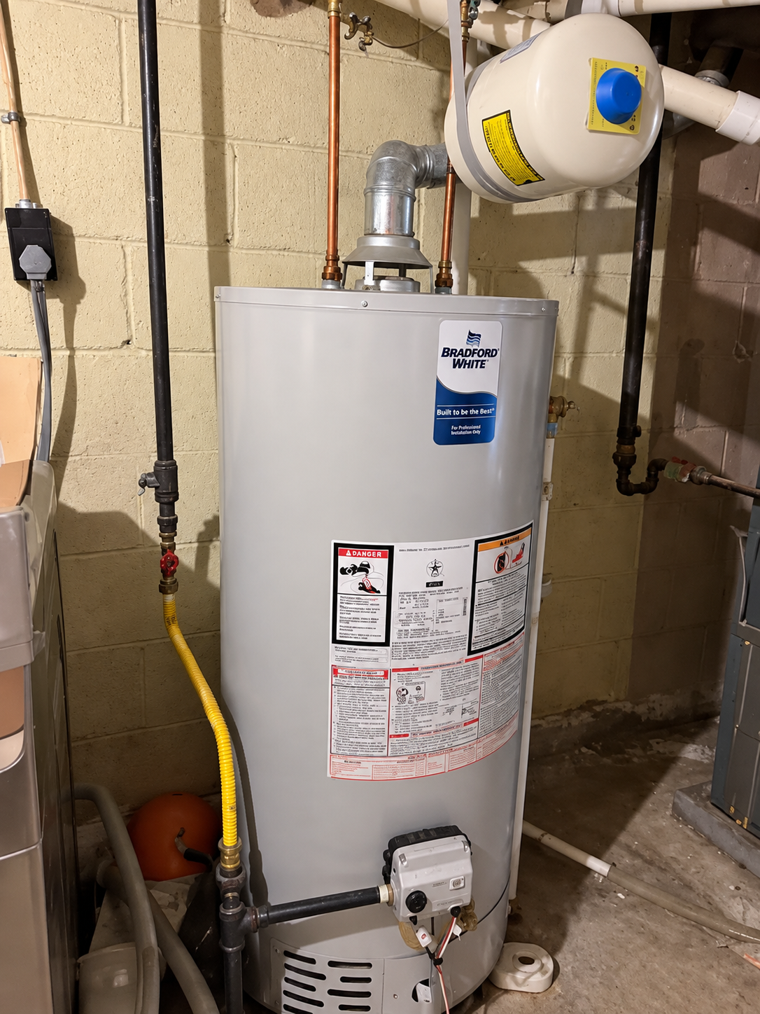 Gas water heater with vent pipe and yellow gas line in a basement utility room