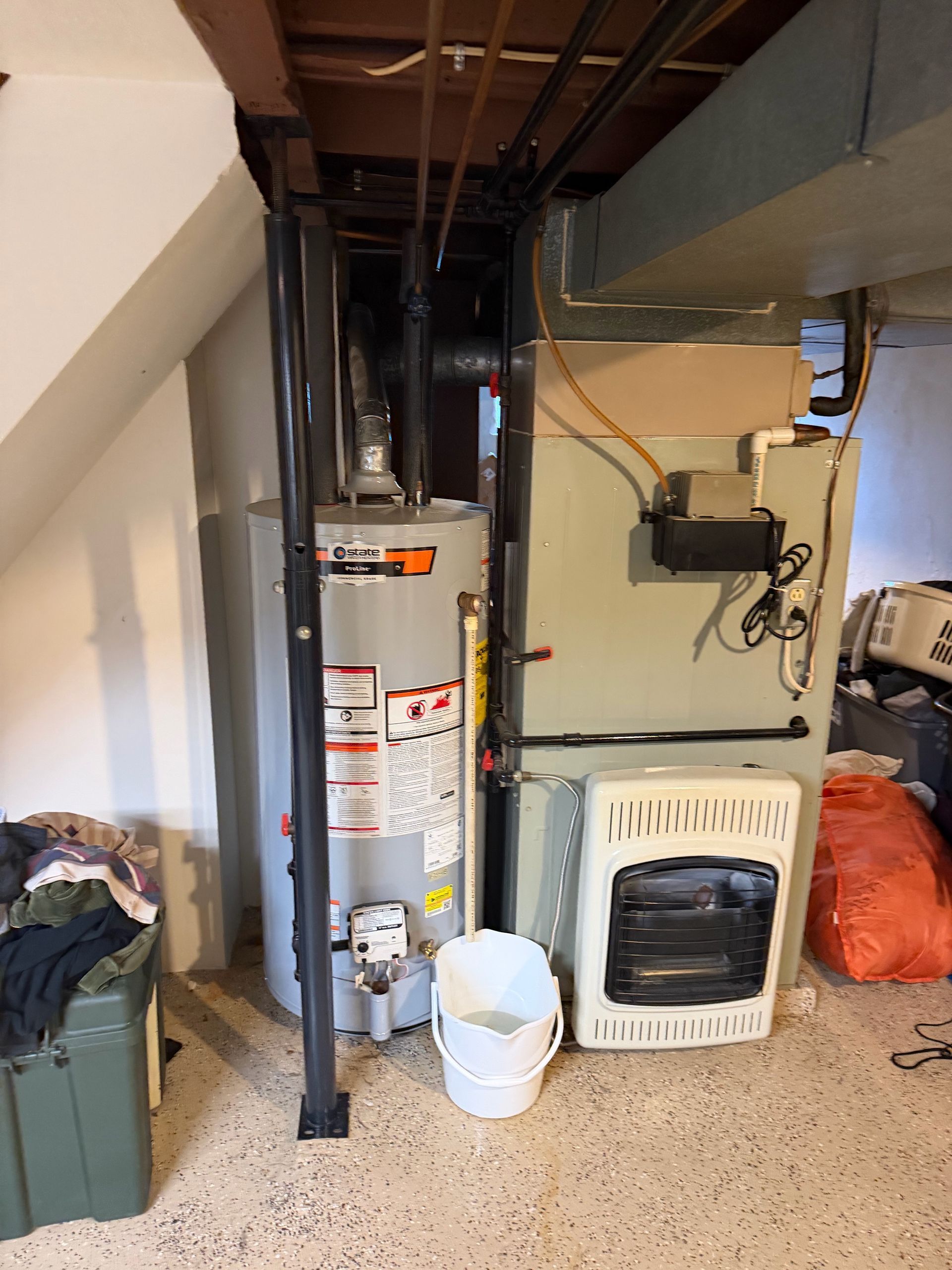 Basement utility area with furnace, water heater, storage bins, and laundry items.