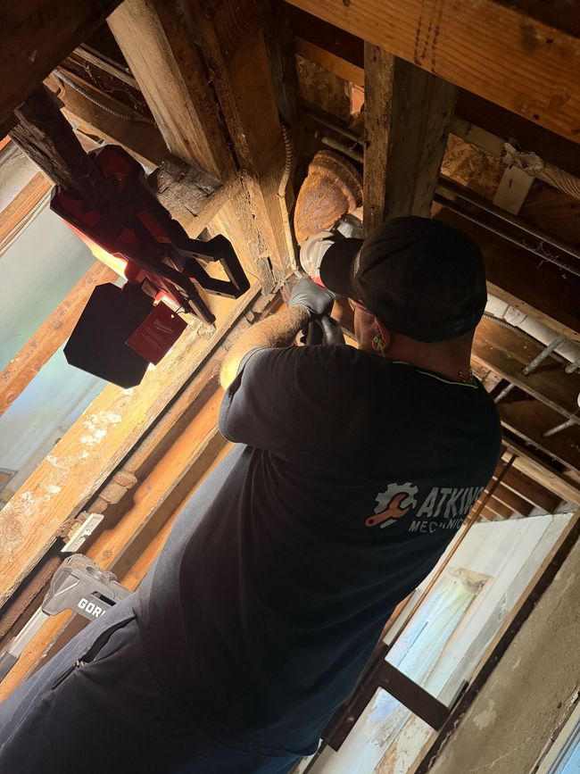 Technician using a manifold gauge set to service an outdoor air conditioning unit.