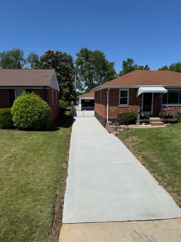 A brick house with a concrete walkway leading to it.