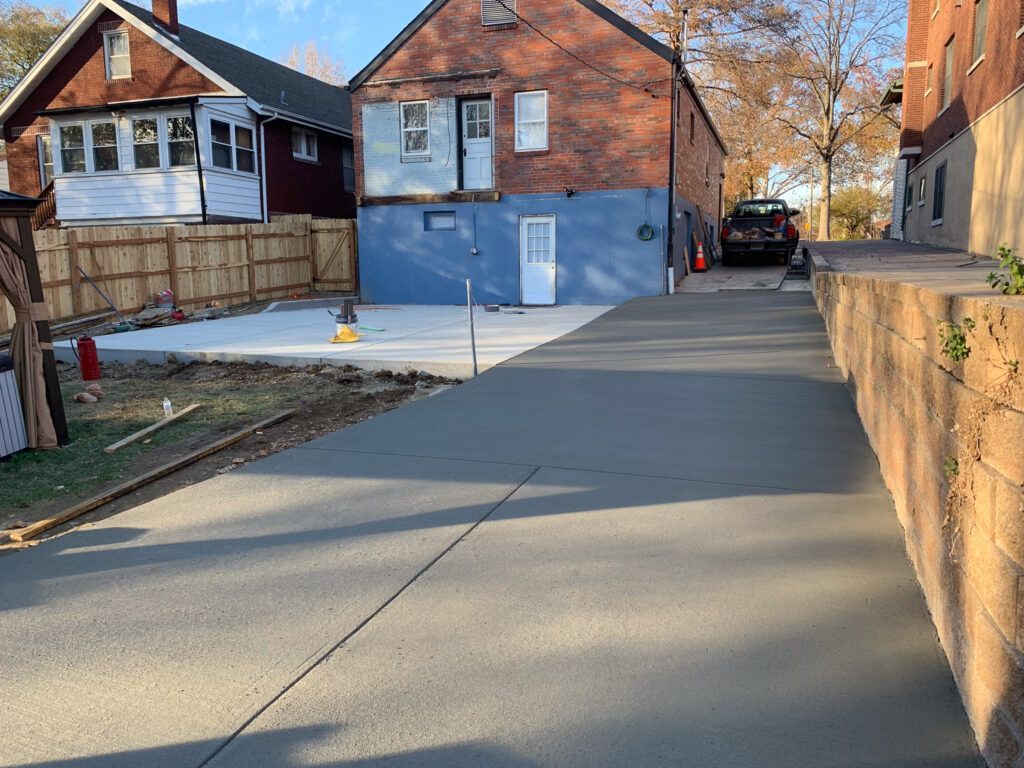 A brick house is being built next to a concrete driveway.