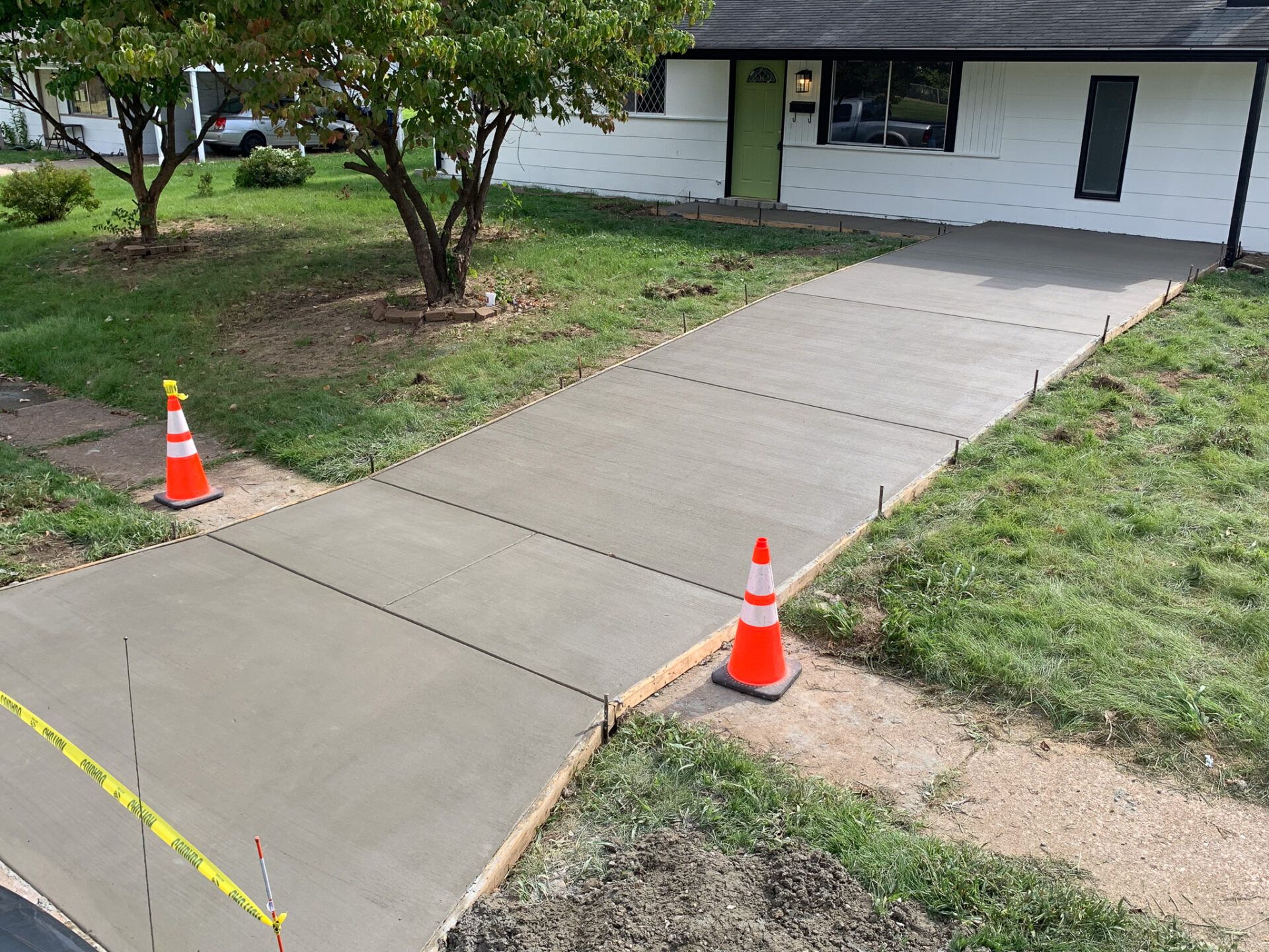 A concrete walkway is being built in front of a house.