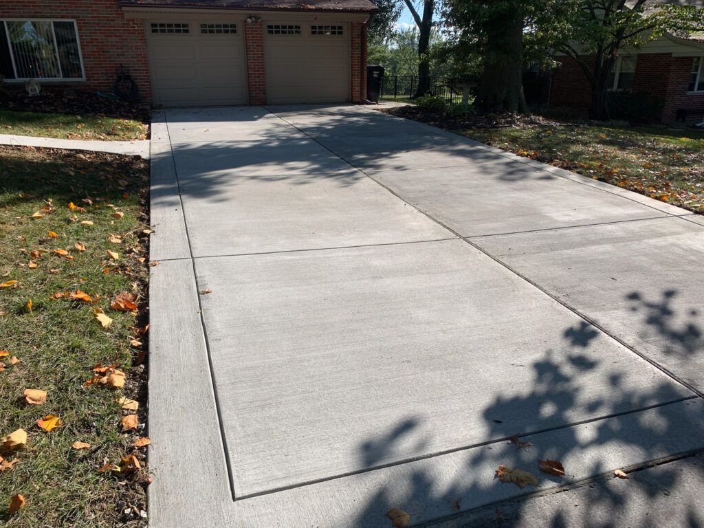 A concrete driveway leading to a house with garage.