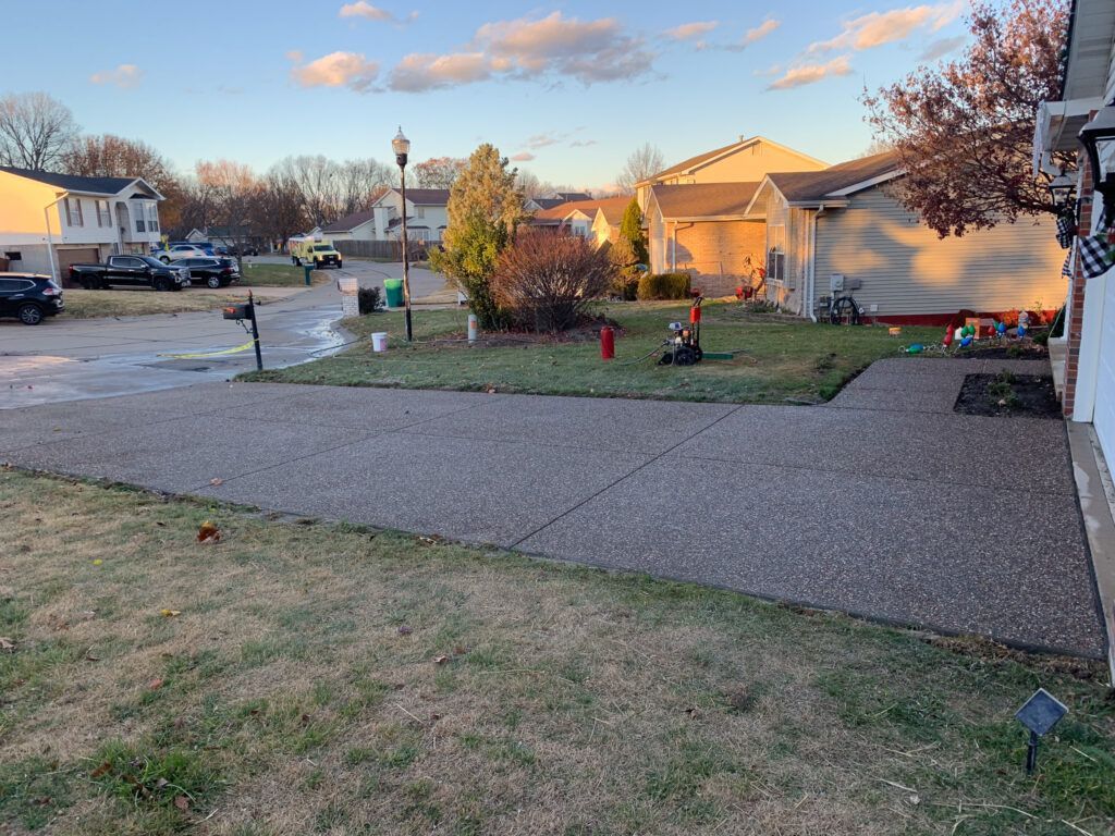 A concrete driveway leading to a house in a residential area.