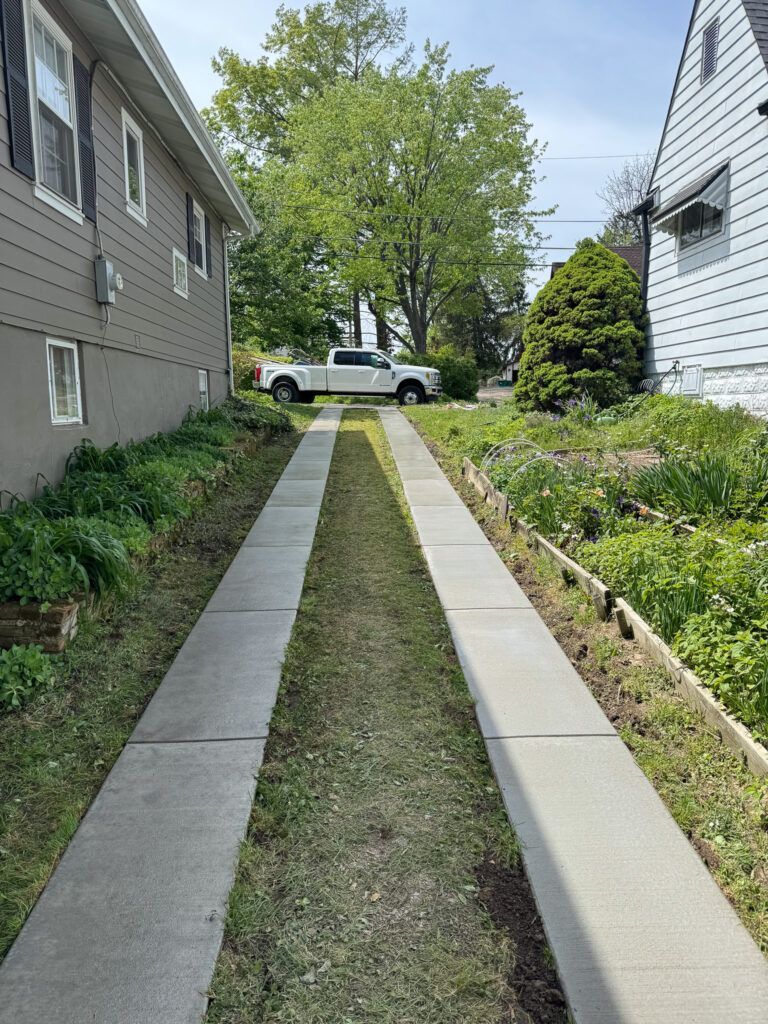 A white truck is parked in the driveway of a house next to a sidewalk.