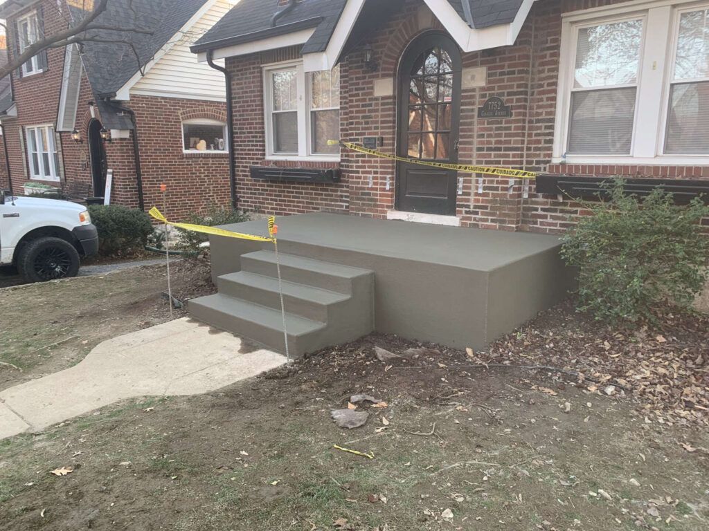 A white truck is parked in front of a brick house with concrete steps.