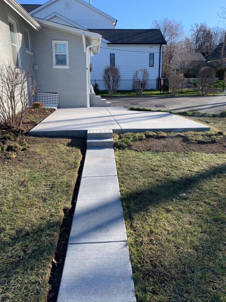 A concrete walkway leading to a house on a sunny day.