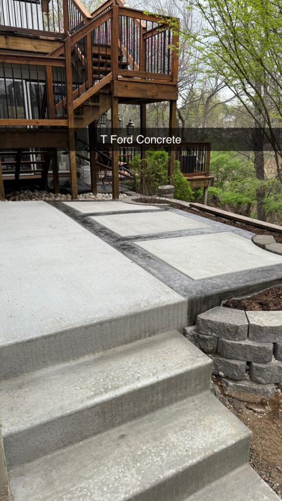A concrete patio with stairs leading up to a wooden deck.