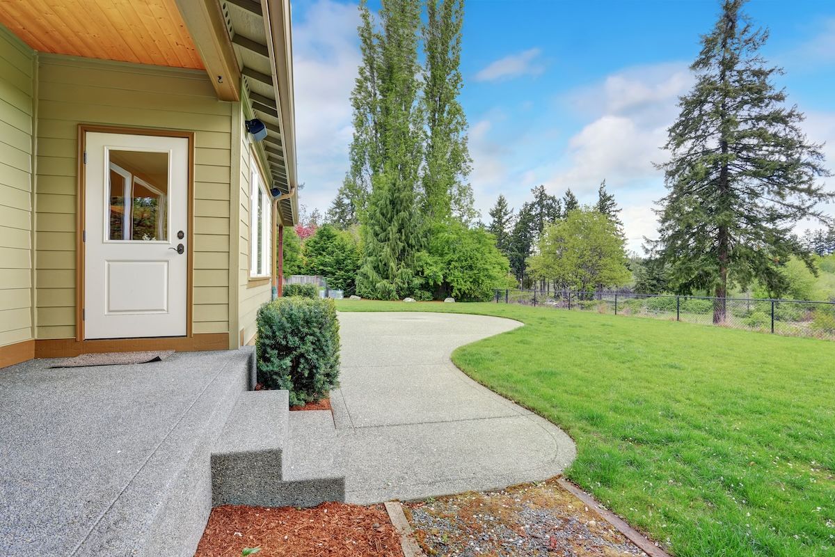 A house with a white door and a concrete walkway leading to it.