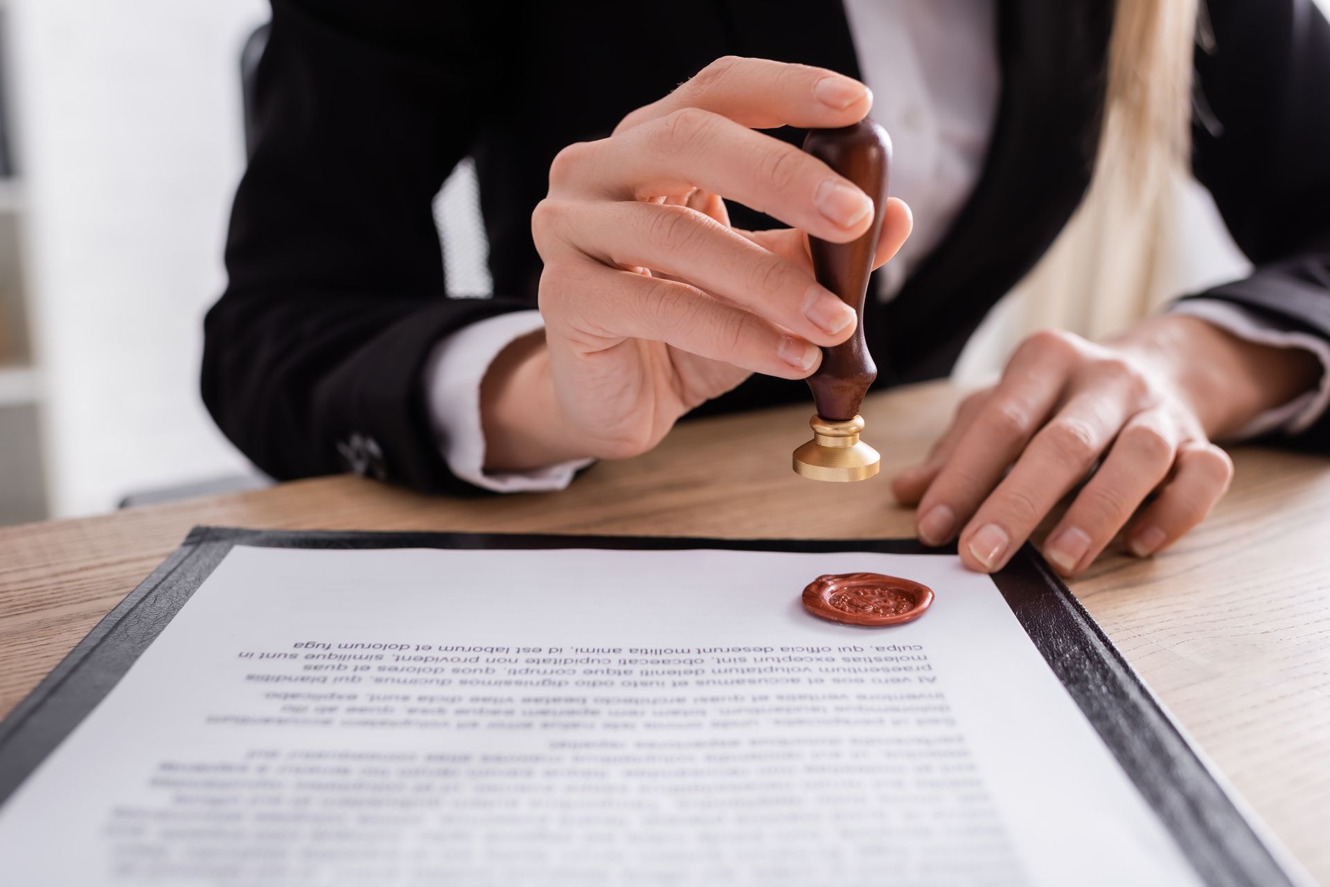 Person stamping a document with a wax seal on a desk