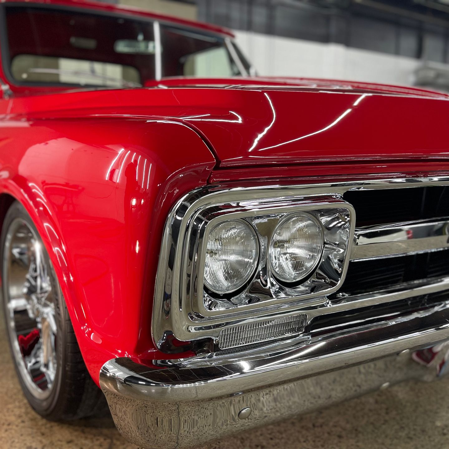 Close-up of a glossy red classic car front fender and chrome headlight assembly