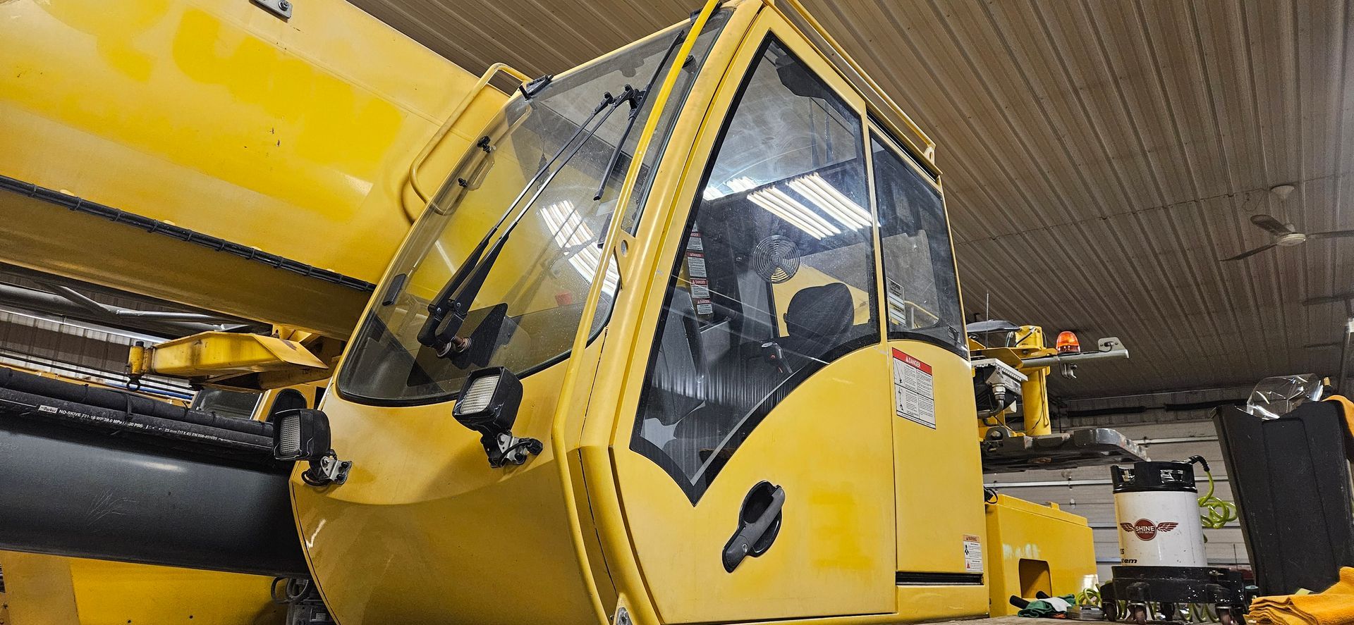 Yellow industrial vehicle with a raised cab parked indoors under a ceiling