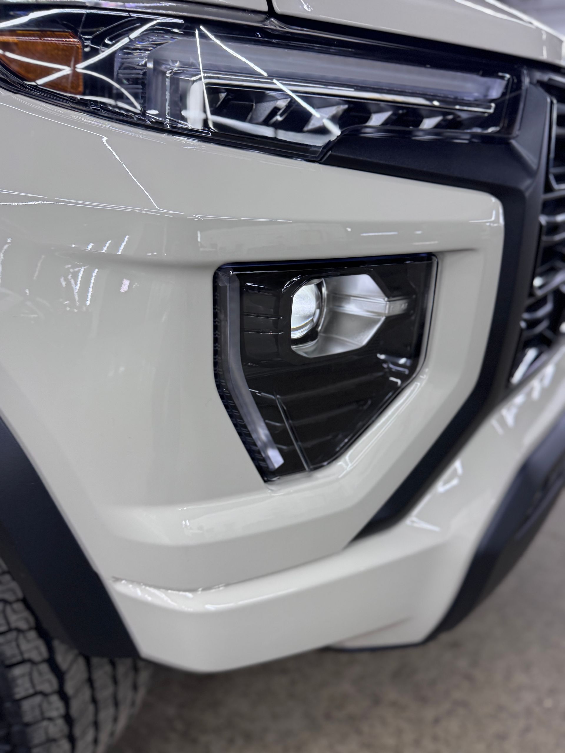Close-up of a white SUV’s front bumper and fog light assembly