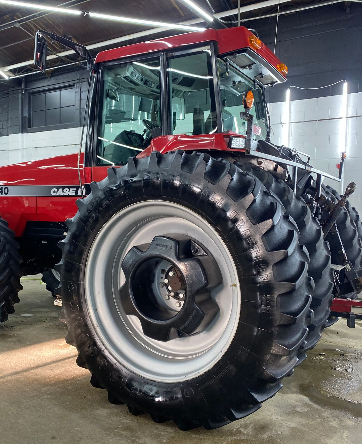 Red tractor with oversized dual rear tires inside a garage or workshop