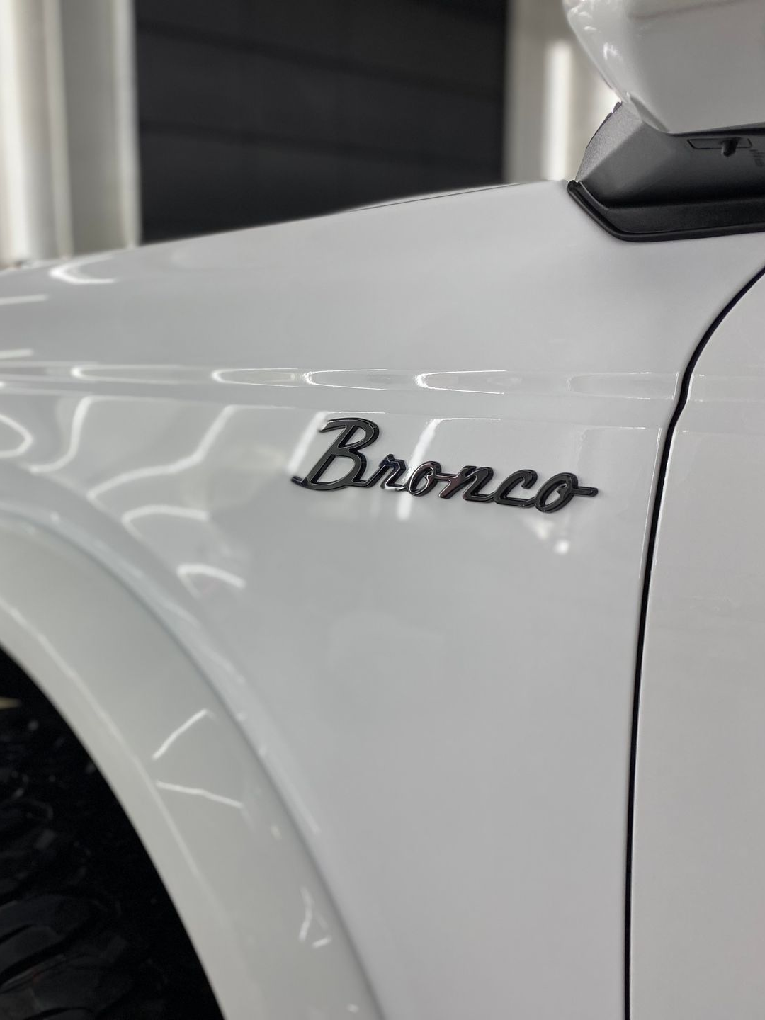 Close-up of a white Ford Bronco badge on a vehicle fender