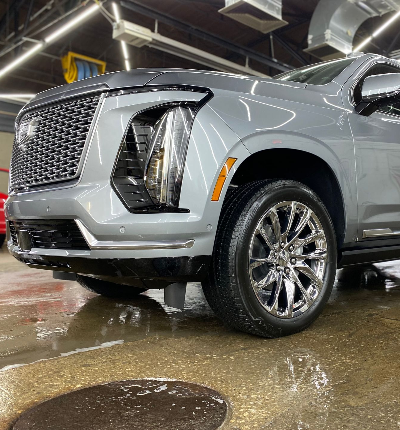 Silver SUV parked indoors on a wet floor, showing its front and side with chrome grille and wheels