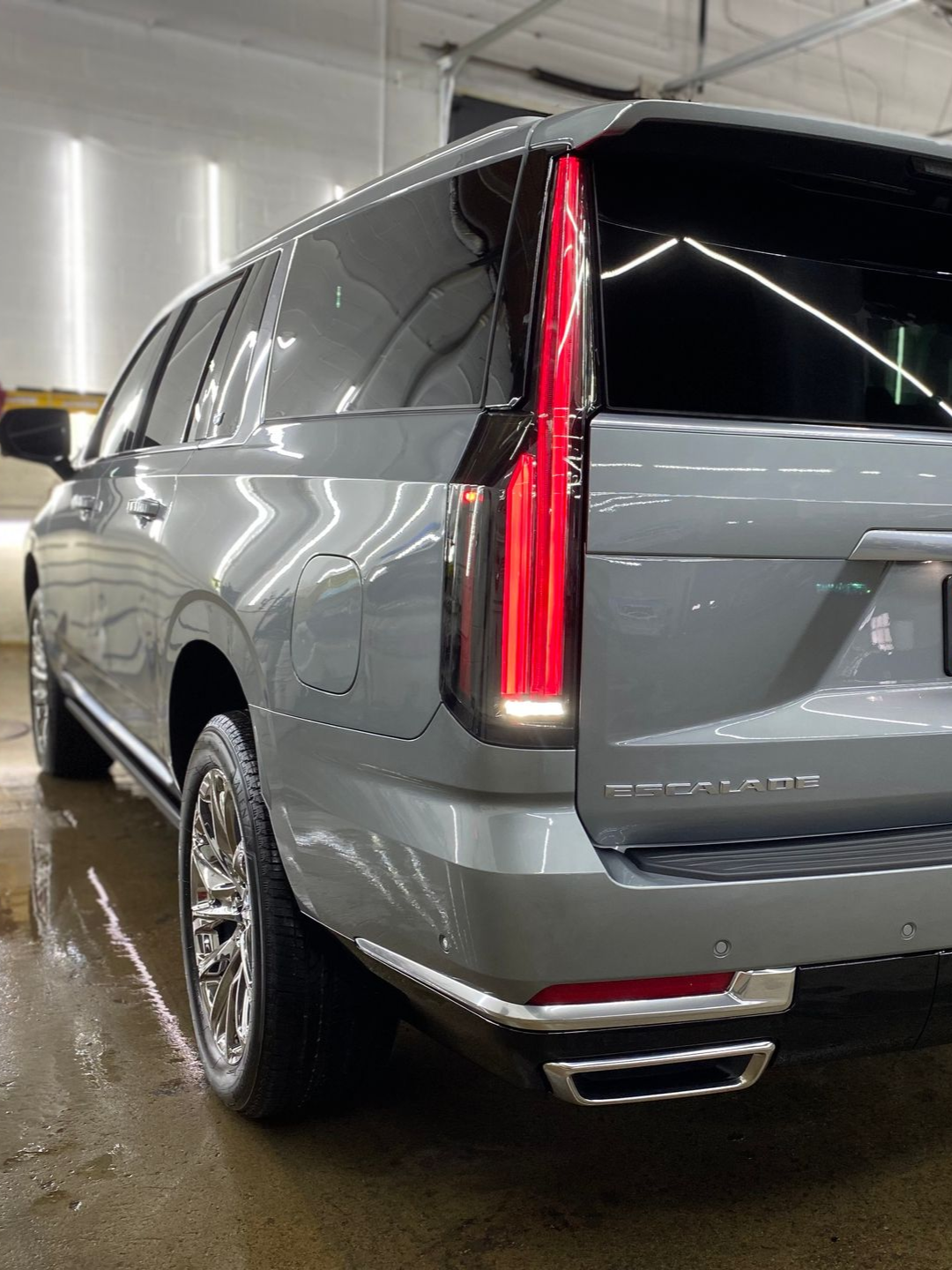 Silver SUV viewed from rear in a car wash, with taillights glowing red.