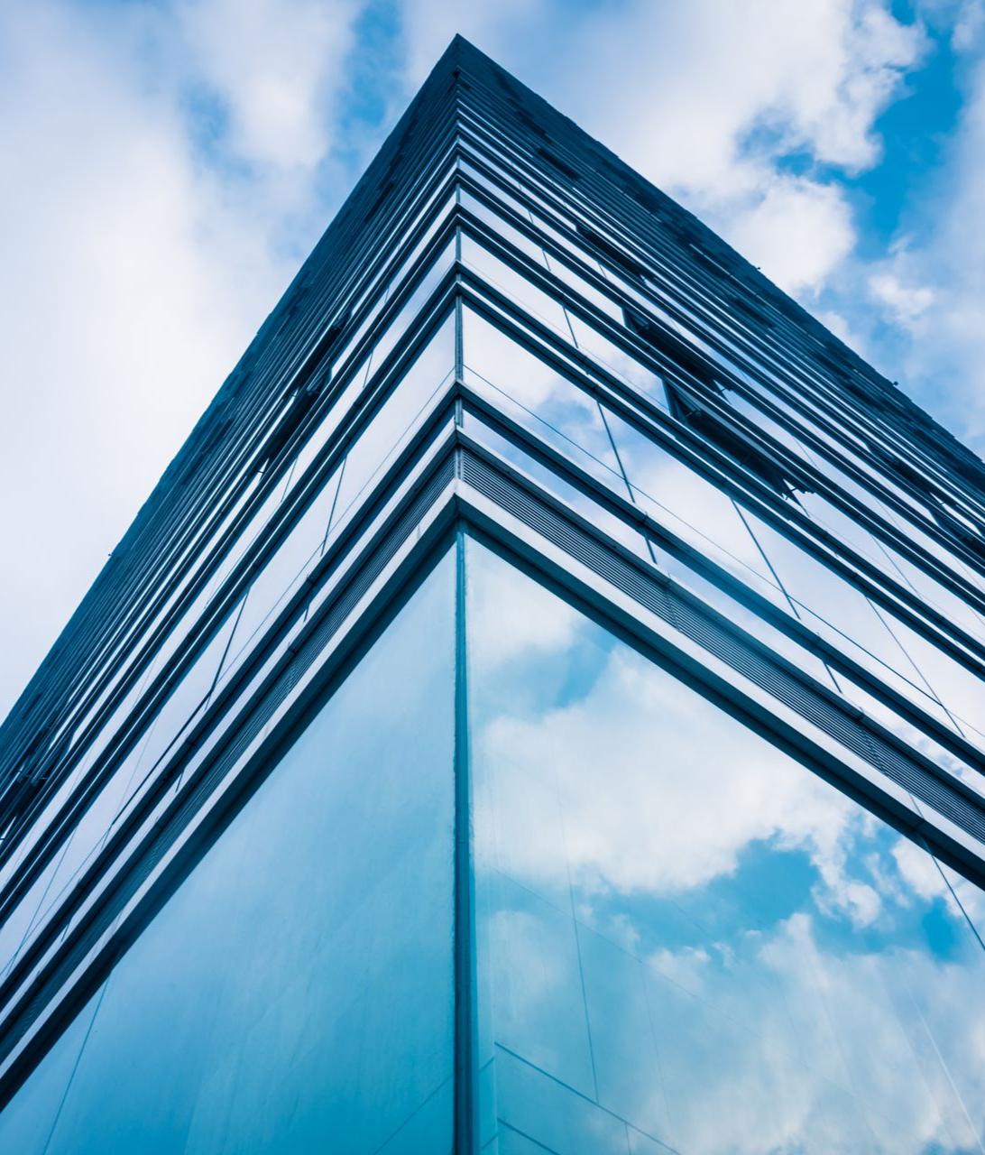 Modern glass skyscraper corner reflecting blue sky and clouds