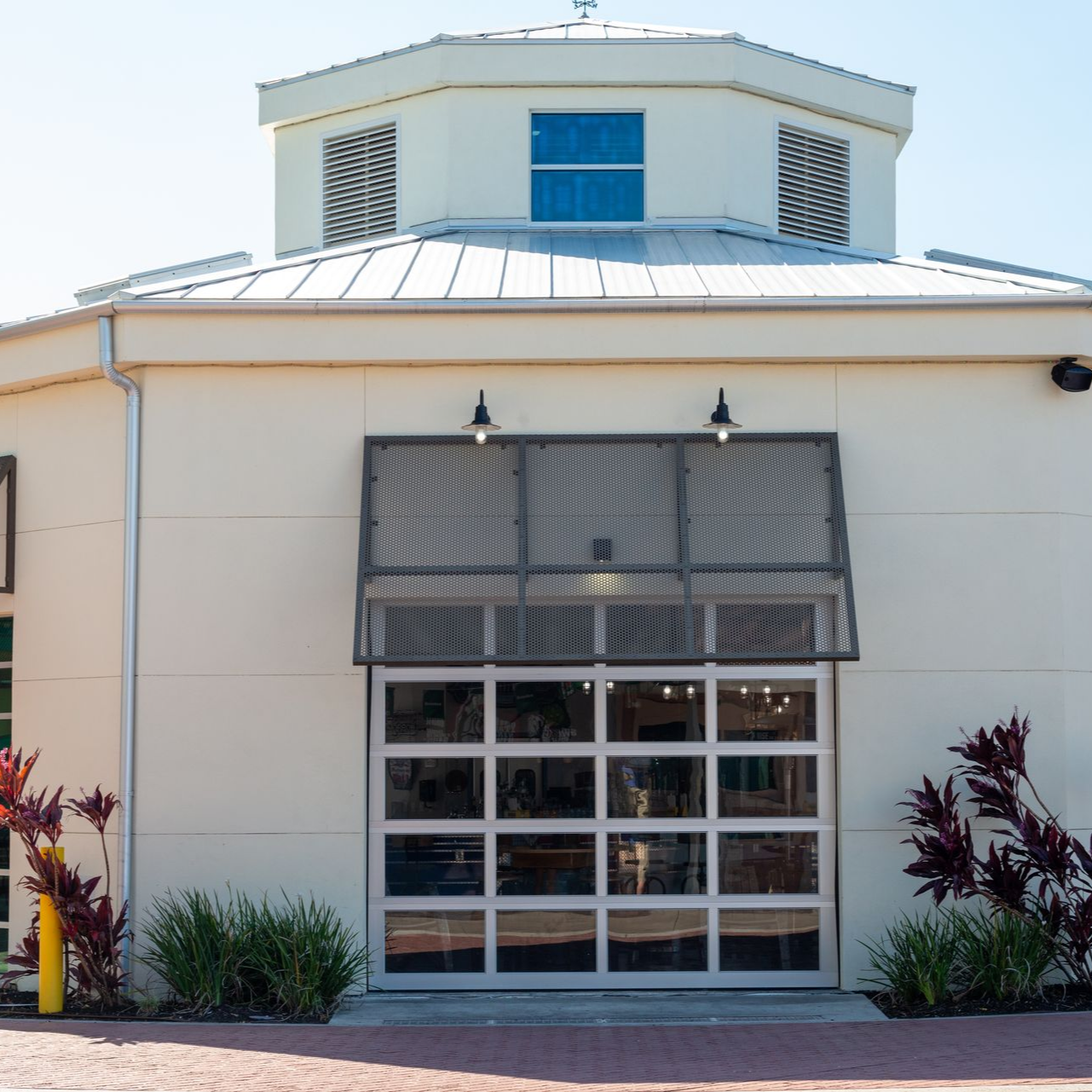 Front view of a white building with a gray garage door, blue windows, and desert landscaping