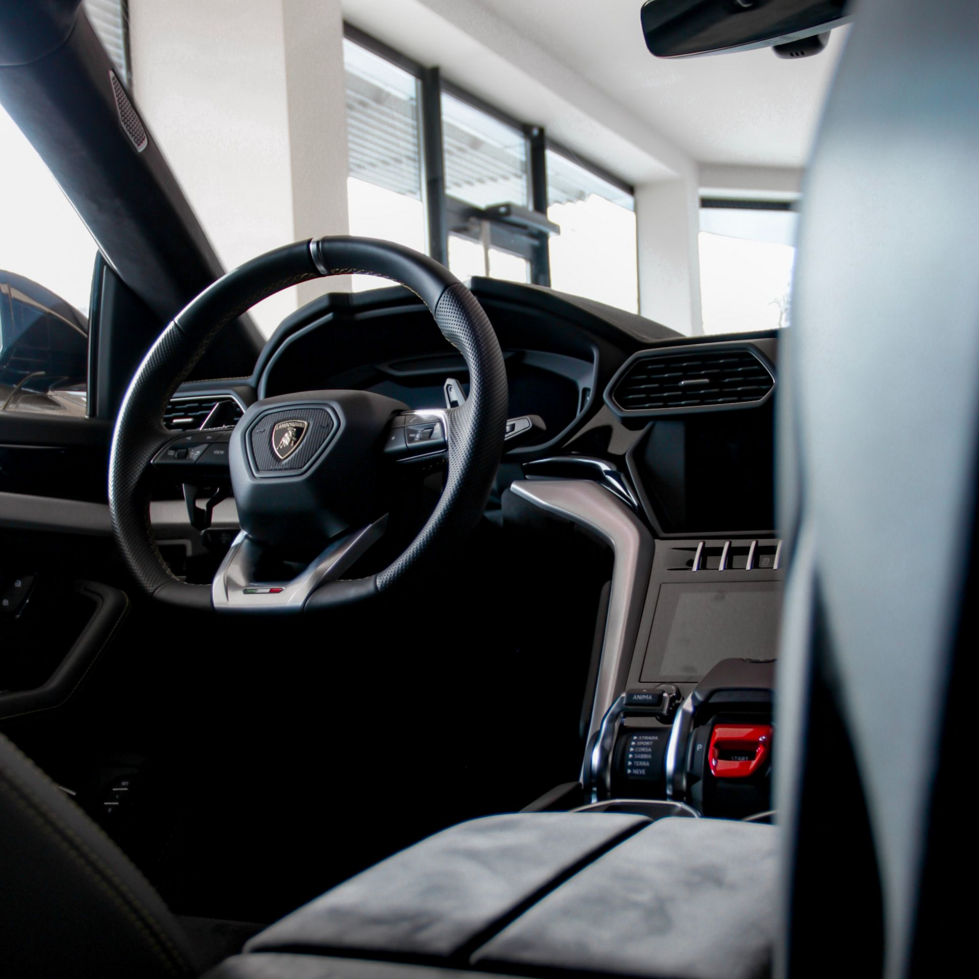 Luxury car interior with black leather seats, steering wheel, and red dashboard accents