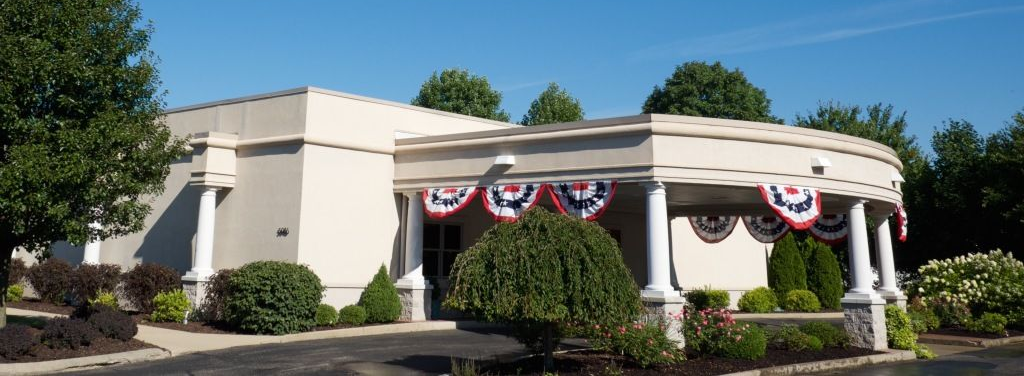 Single-story beige building with red, white, and blue bunting under a clear blue sky