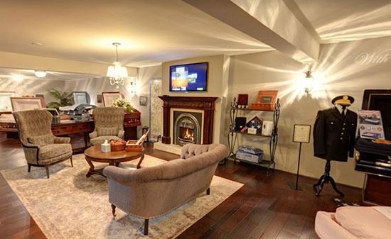 A funeral home visitation room featuring a fireplace, seating area, and a mannequin dressed in a formal suit.