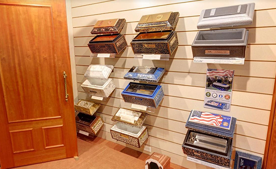 A display wall in a funeral home showcasing various memorial urns and small caskets in different styles and materials.