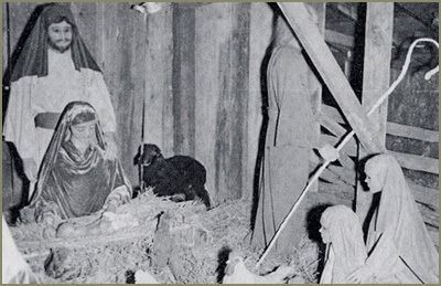 A Nativity scene featuring figures in traditional robes gathered around a baby in a manger, with a small dog and animals.