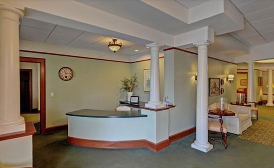 A reception desk with a curved counter in a lobby with light green walls and classical columns.